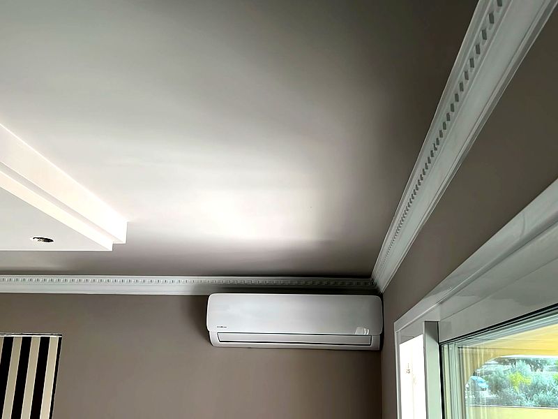 Split MundoClima integrado con molduras clásicas en salón luminoso
