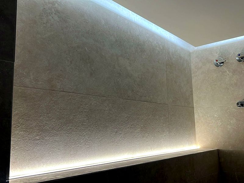 Iluminación perimetral LED en baño revestido en travertino